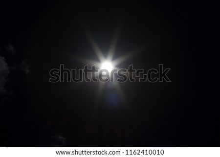 An underexposed shot of the sun at noon - sunbeams and flairs Royalty-Free Stock Photo #1162410010