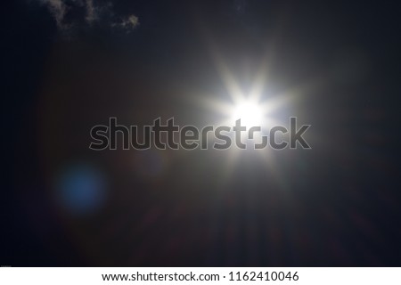 An underexposed shot of the sun at noon - sunbeams and flairs Royalty-Free Stock Photo #1162410046