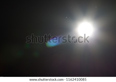An underexposed shot of the sun at noon - sunbeams and flairs Royalty-Free Stock Photo #1162410085