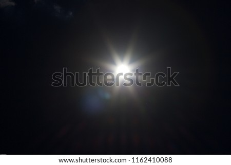 An underexposed shot of the sun at noon - sunbeams and flairs Royalty-Free Stock Photo #1162410088