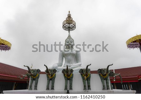 White Buddha statue meditating With elephants statue At Doi Monta Tenple, Mae Sot, Tak, Thailand.