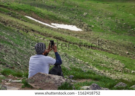 young man taking phone photo sitting on grass