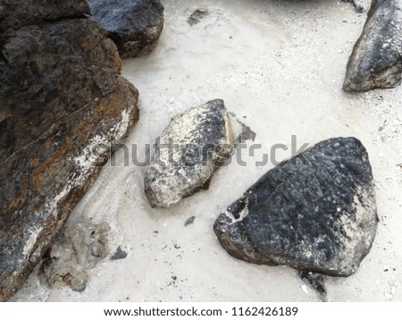 Big stone rocks on sand beach near blue water on island