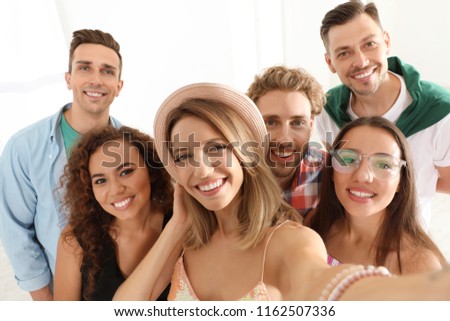 Group of happy young people taking selfie indoors