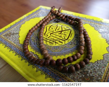 Yellow Koran in hand. Arabic word translation : The Holy Al Quran (holy book of Muslims) - public item of all muslims