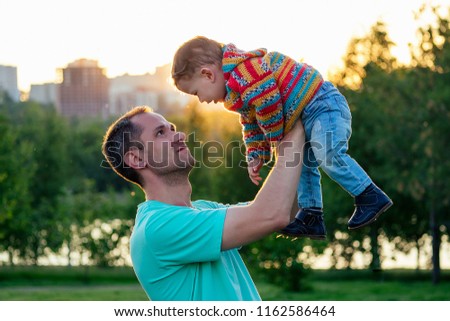 Father holds baby son in her arms in the open air the summer in park