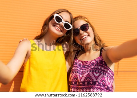 fashion, leisure and people concept - smiling teenage girls taking selfie outdoors in summer