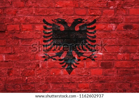 Flag of Albania over an old brick wall background, surface