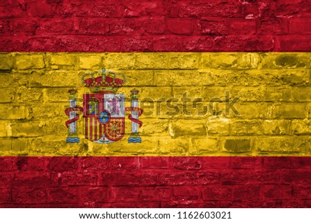 Flag of Spain over an old brick wall background, surface.