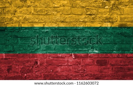Flag of Lithuania over an old brick wall background, surface. Yellow, green and red flag