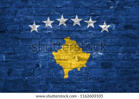 Flag of Kosovo over an old brick wall background, surface.