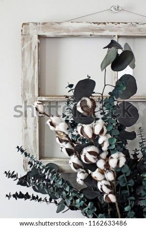 Eucalyptus and cotton stem arrangement in front of an old farmhouse window.  