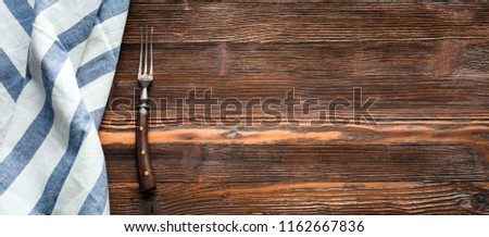 An old fork and napkin with an empty tag on a rustic wooden background, long banner