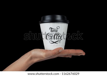 Female hand with white coffee cup on palm isolated on black with Time For Coffee hand lettering