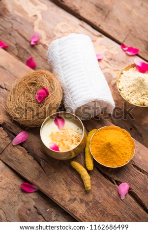 Ayurvedic face pack/mask using Gram Flour/besan, Haldi & milk ubtan placed in brass bowls with rose petals, scrub  and white napkin. selective focus
