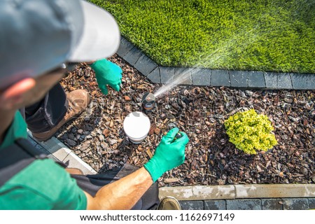 Adjusting Lawn Sprinkler by Professional Garden Irrigation Technician. Top View. Royalty-Free Stock Photo #1162697149