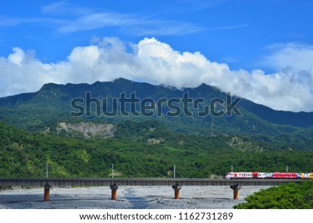 Taiwan, Taitung City, the elevated railway on the river sand, fast-moving trains and moving blue sky, the background is rolling mountains, is a beautiful picture.