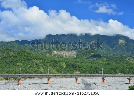 Taiwan, Taitung City, the elevated railway on the river sand, fast-moving trains and moving blue sky, the background is rolling mountains, is a beautiful picture.