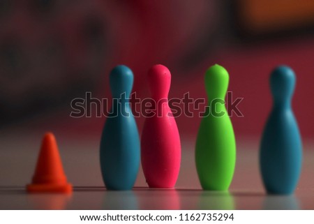 close up of miniature bowling pins and a traffic cone in a blurry colorful background
