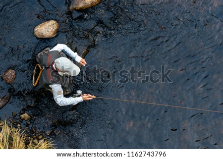 Fly fisherman using flyfishing rod in beautiful river Royalty-Free Stock Photo #1162743796