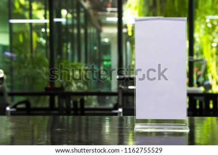 Stand mock up acrylic tent card menu frame on wood table in restaurant background. Point of purchase advertising concept.