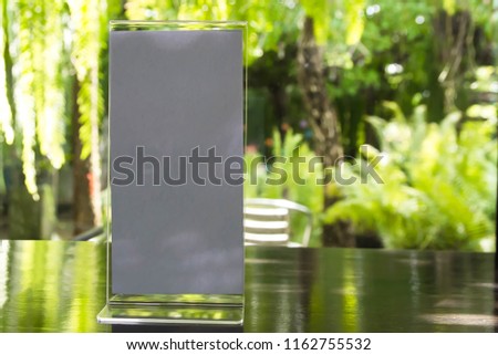 Stand mock up acrylic tent card menu frame on wood table in restaurant background. Point of purchase advertising concept.