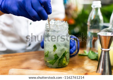 making of a mojito in a wooden cutting board. where all ingridients and tools are at sight. Specially lemons,  mint leafs, ice, soda and rum. the picture was taken in Curaçao, Dutch caribbean.