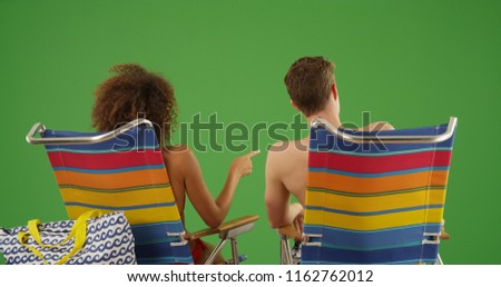 Rear view portrait of couple sitting on beach chairs on green screen
