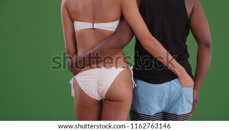 Rear view of loving black couple in swimwear embracing on green screen