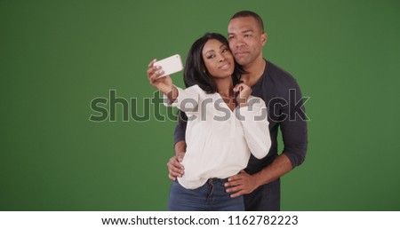 Black couple posing for selfies on green screen