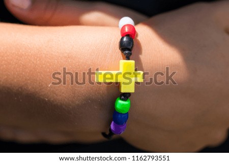 Colorful fashion bracelet on woman hand with a cross.