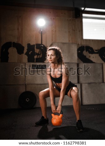 The girl in the gym doing exercises with weights. Close-up photo. The photograph illustrates the sport and a healthy lifestyle.
