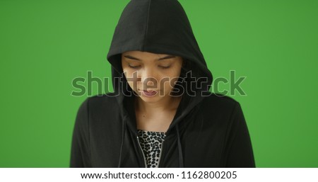 A depressed young girl in hoodie poses for a portrait on green screen