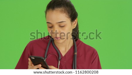 A medical professional uses her smart phone on green screen