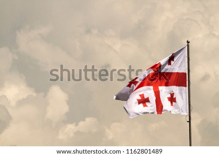 Georgian flag blowing in the breeze on a mistic cloudy sky background.