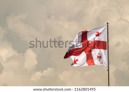 Georgian flag blowing in the breeze on a mistic cloudy sky background.
