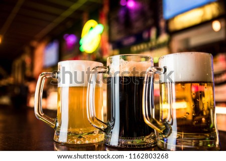 Three glasses of beer on a table in bar background