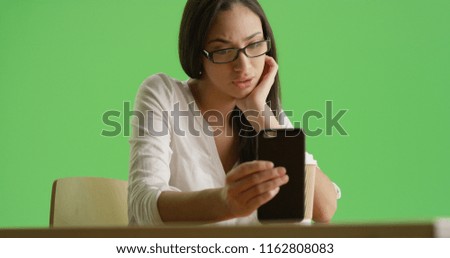 A Hispanic millennial uses her smart phone on green screen
