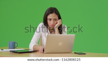 A Latina woman looking sad as she uses her laptop on green screen