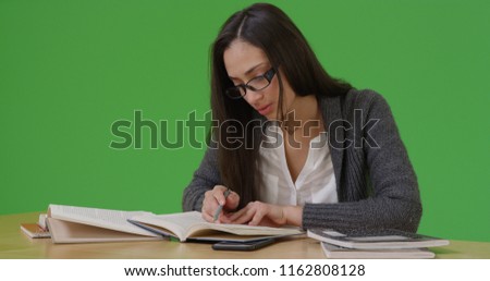 Latina college student does her homework at her desk on green screen