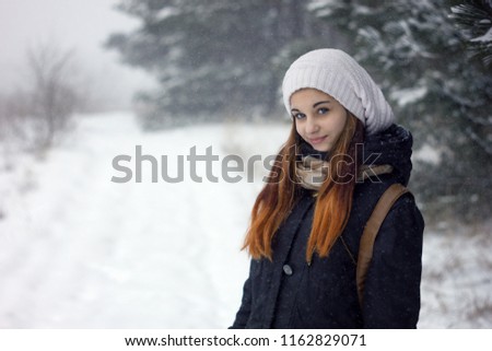 portrait of girl in heavy snowfall, beauty baby girl in sweater and hat, winter day with heavy snowfall, winter confusion