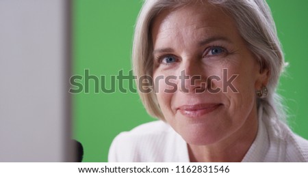 Beautiful mid aged white woman applying makeup looking at camera on greenscreen