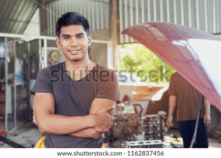 The car repairer is checking the car for maintenance. People who work on cars in the garage do their own homework. Check / inspect the engine for trouble
