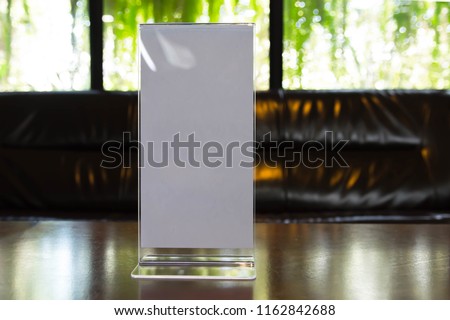 Stand mock up acrylic tent card menu frame on wood table in restaurant background. Point of purchase advertising concept.
