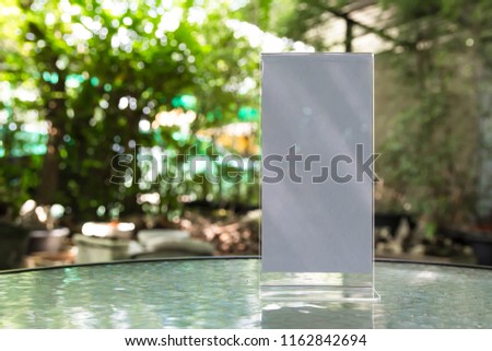 Stand mock up acrylic tent card menu frame on wood table in restaurant background.Point of purchase advertising concept.