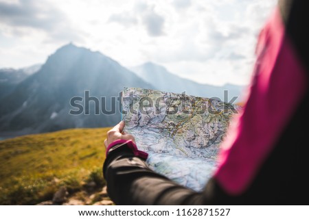 Adventurous Girl navigating in with a Topographic Map in the beautiful Mountains of the Austrian Alps Royalty-Free Stock Photo #1162871527