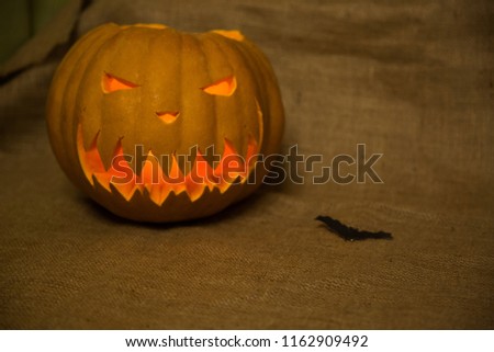 Halloween symbol jack-o-lantern and bat. Scary carved pumpkin with burning candles. Copy space. 