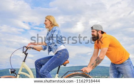 Girl cycling while man support her. Feel impulse to start moving. Woman rides bicycle sky background. Push and promoting. Impulse to move. Man pushes girl ride bike. Support helps believe in yourself.