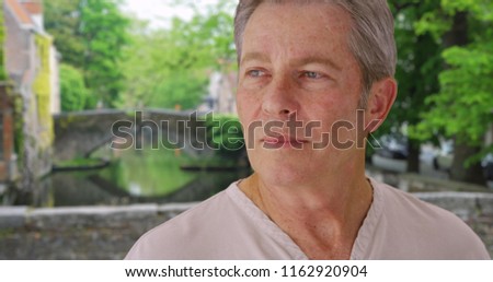 Humorless old white man in Bruges looks around glumly  Royalty-Free Stock Photo #1162920904