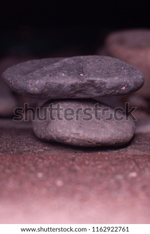 Close up shot of two rocks balancing on top of each other on detailed concrete floor with smooth depth of field. 